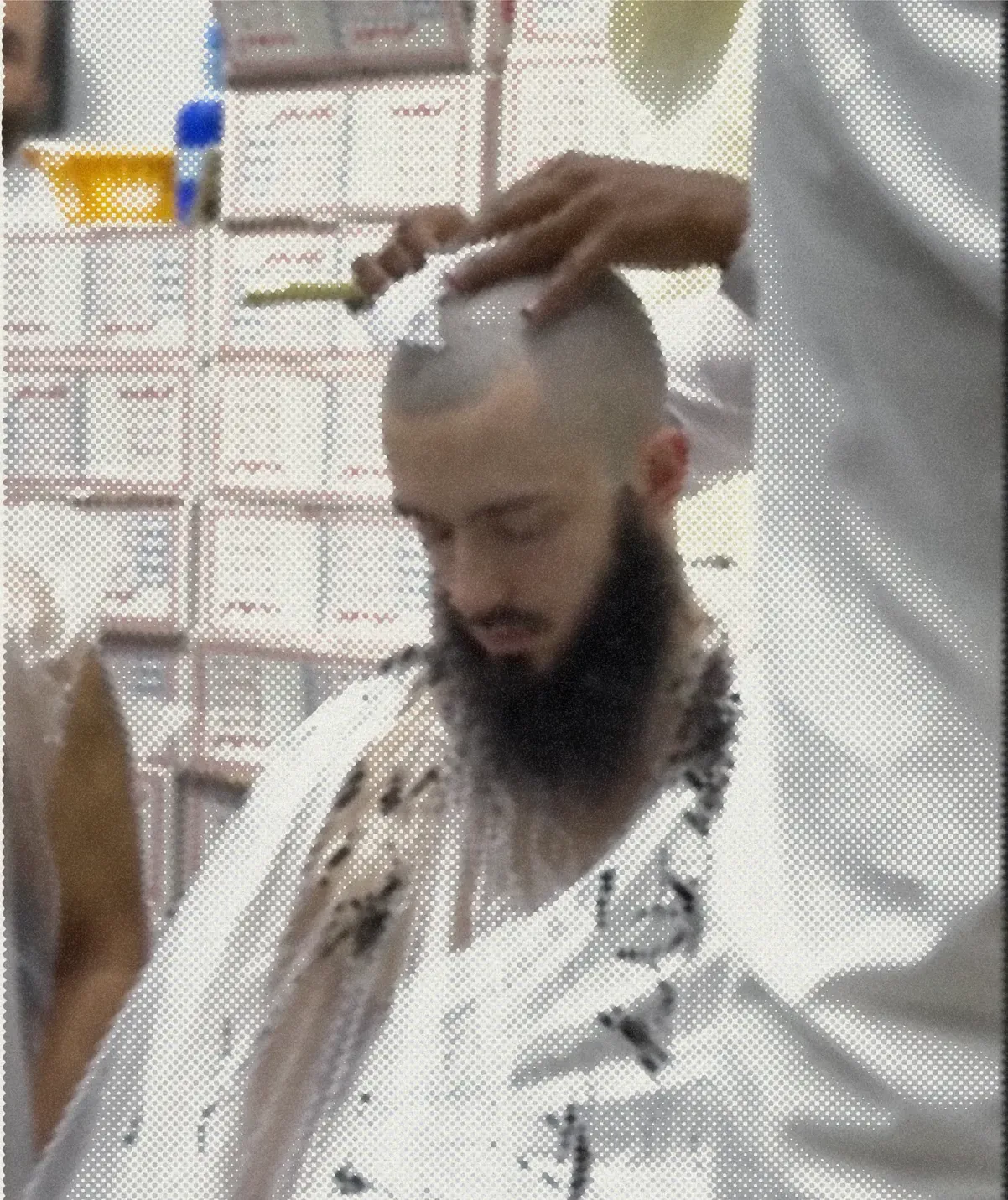 A head being shaved in a barber’s chair, the clippers coming down from above.